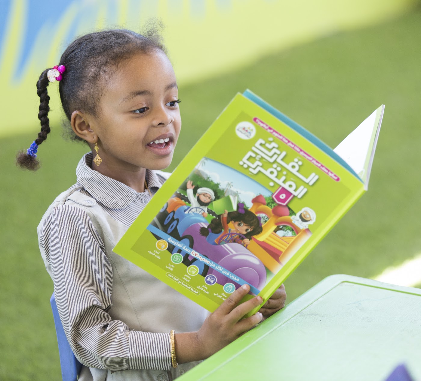 طالبة تضحك وهي تقرأ كتاب القارئ العبقري