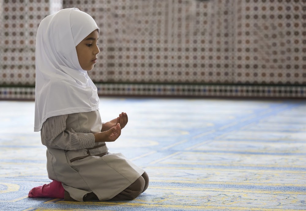 طفلة جالسة تدعو بعد الصلاة