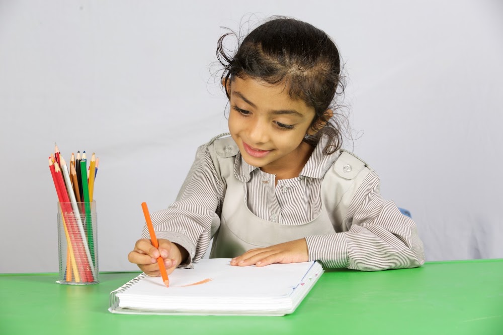 طالبة تكتب بقلم ملوّن مبتسمة